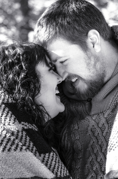 a happy couple giggles as they touch foreheads