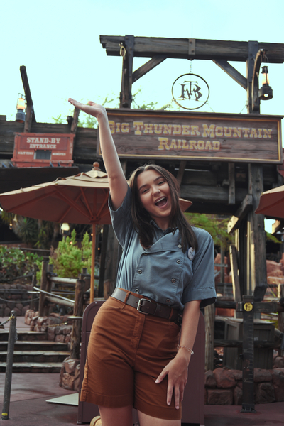 a Disney Cast Member poses outside of Big Thunder Mountain Railroad